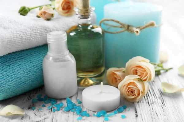 Spa products with towels, oil, candle and roses